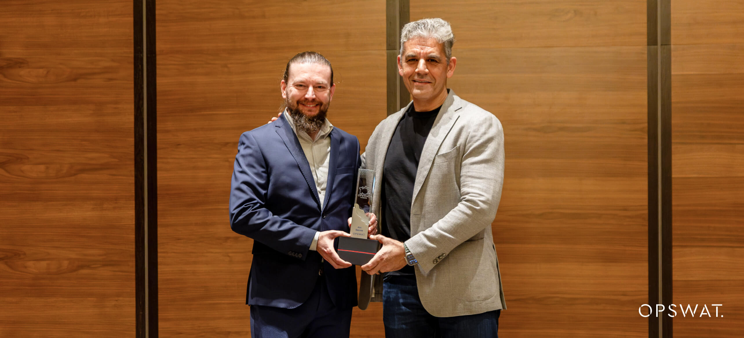 重要インフラのサイバーセキュリティにおけるOPSWAT ルーマニアの役割を象徴する賞を手にする2人。