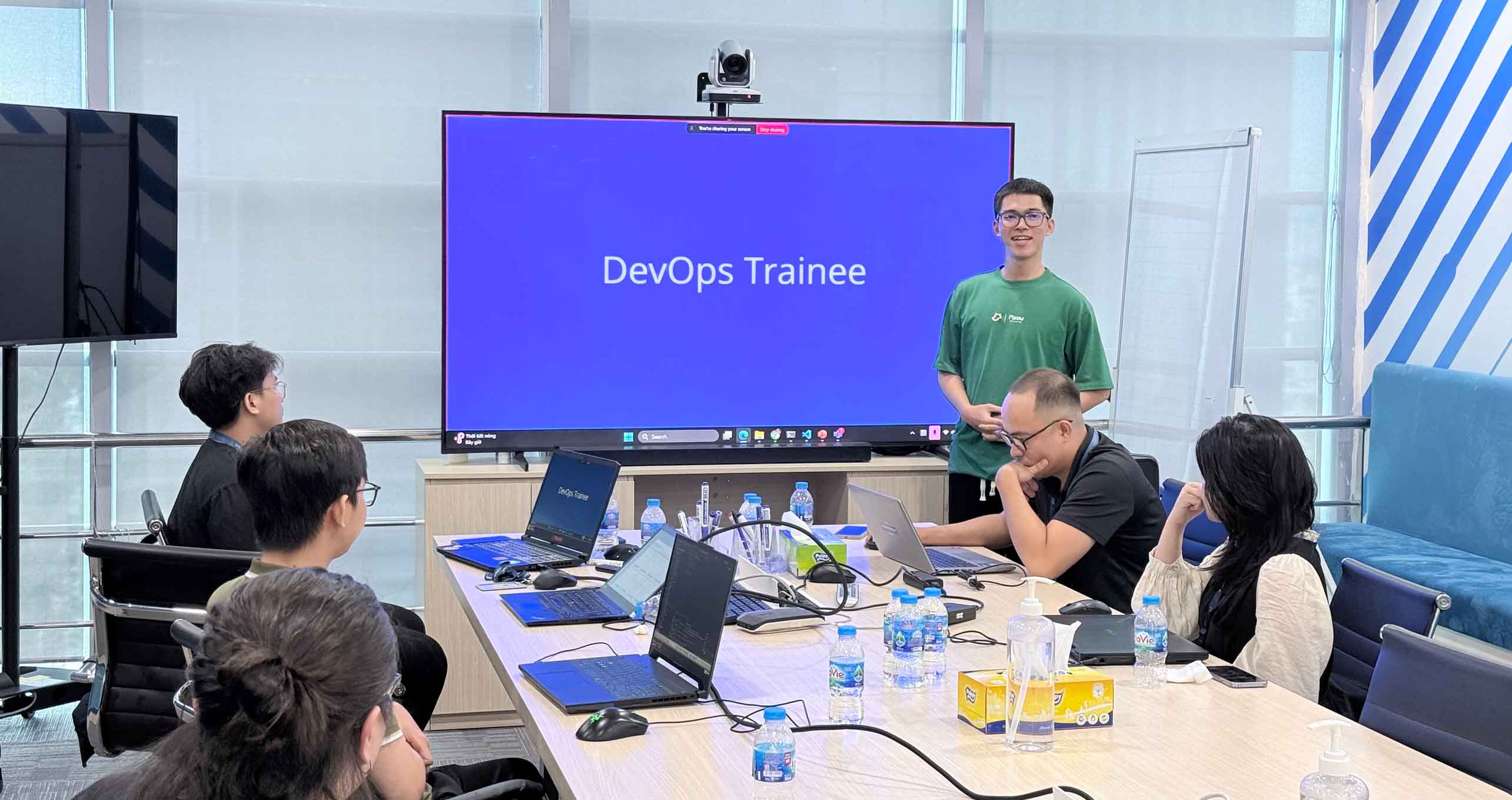 Nhóm thực tập sinh trong phòng họp với DevOps Trainee trên màn hình, một phần của OPSWAT Kinh nghiệm thực tập DevOps và CloudOps