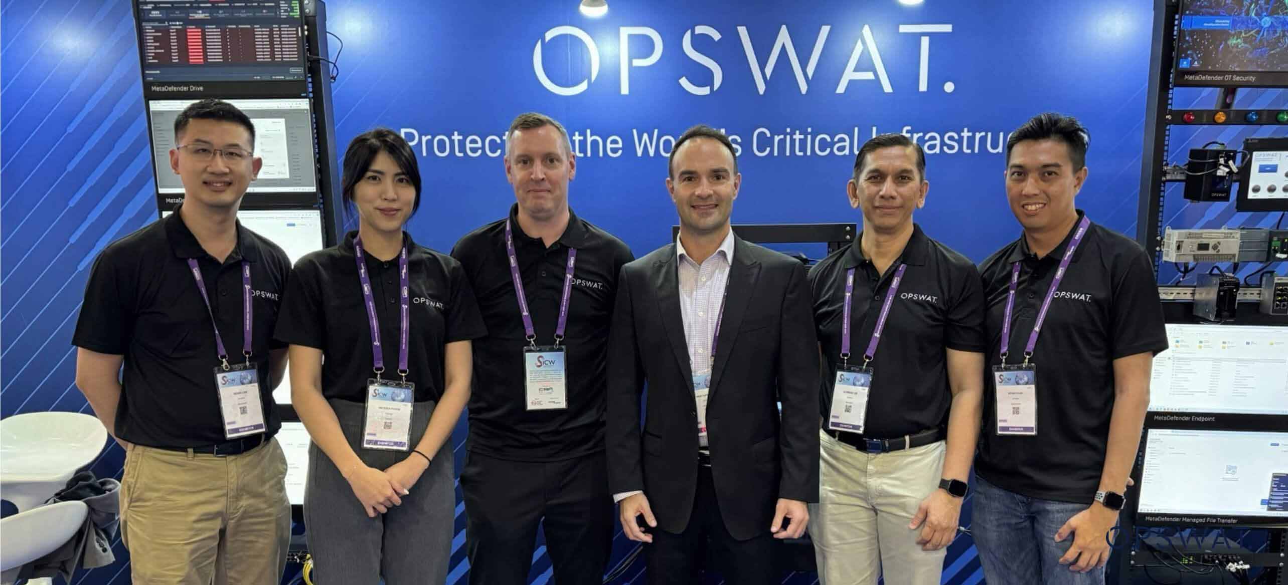 OPSWAT Teammitglieder posieren an einem Konferenzstand, der für Lösungen zum Schutz kritischer Infrastrukturen wirbt