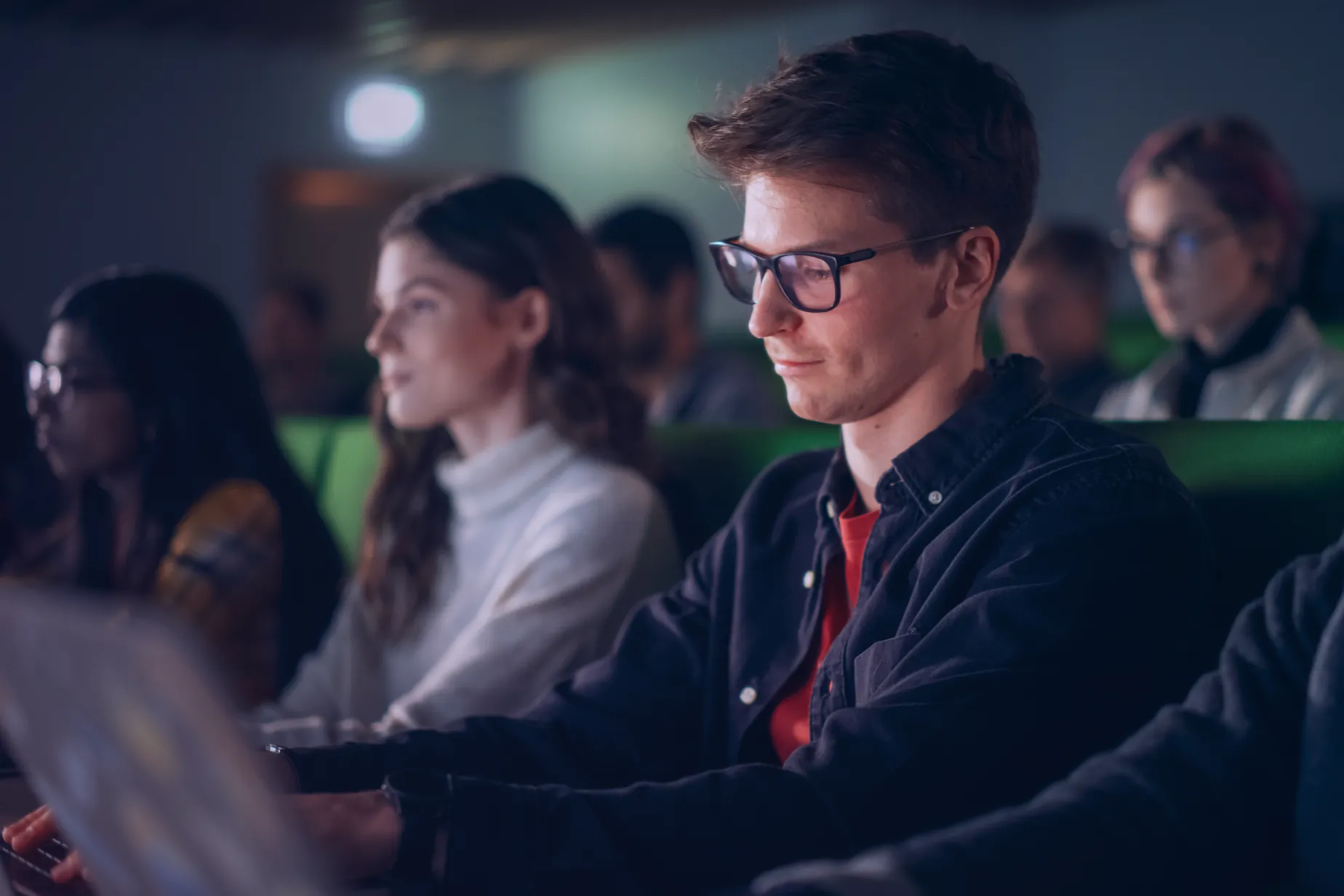 Estudante concentrado a tomar notas durante uma aula sobre cibersegurança numa sala de aula