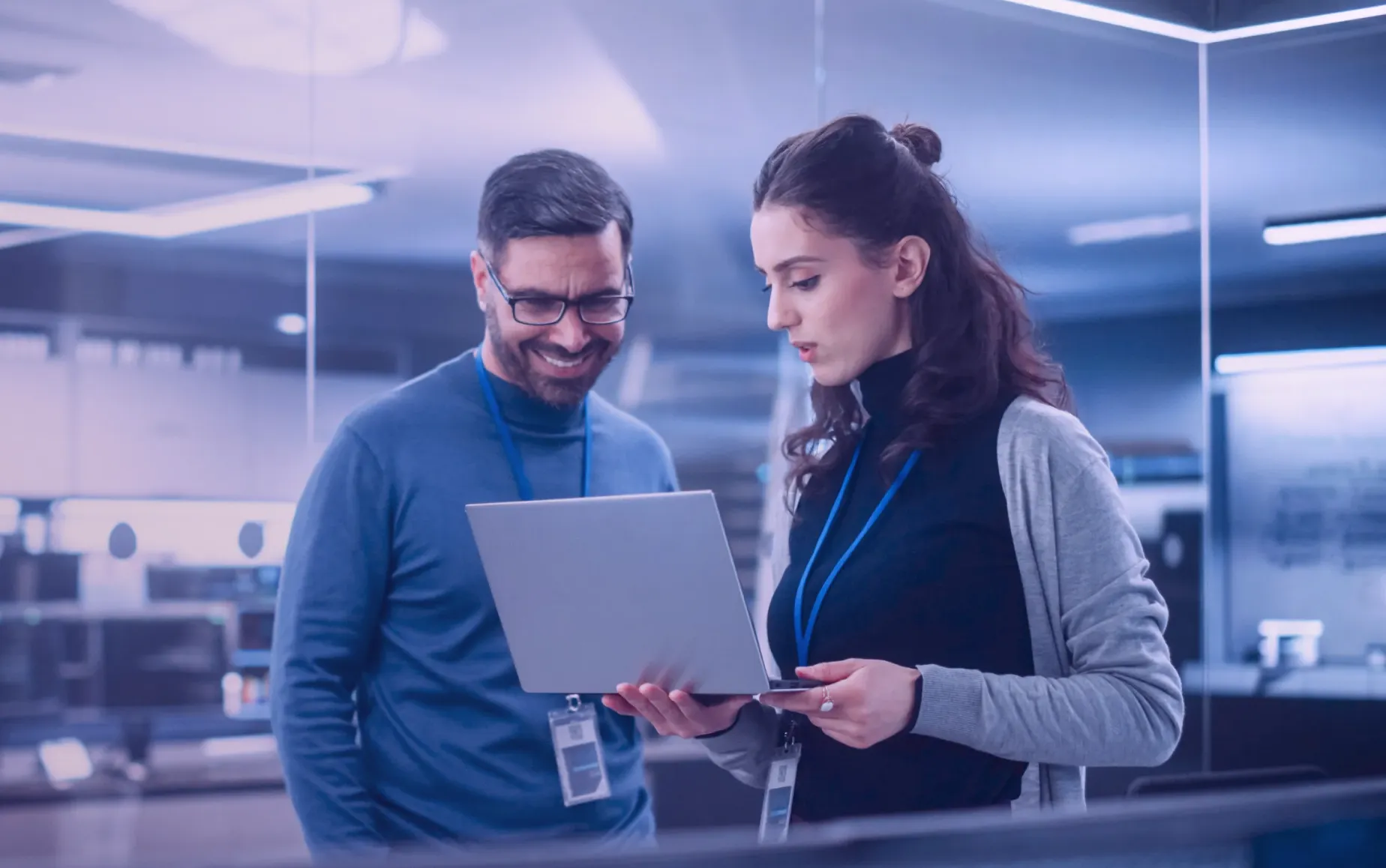 Dois profissionais de TI discutem avaliações de risco cibernético enquanto analisam dados num computador portátil num espaço de trabalho seguro