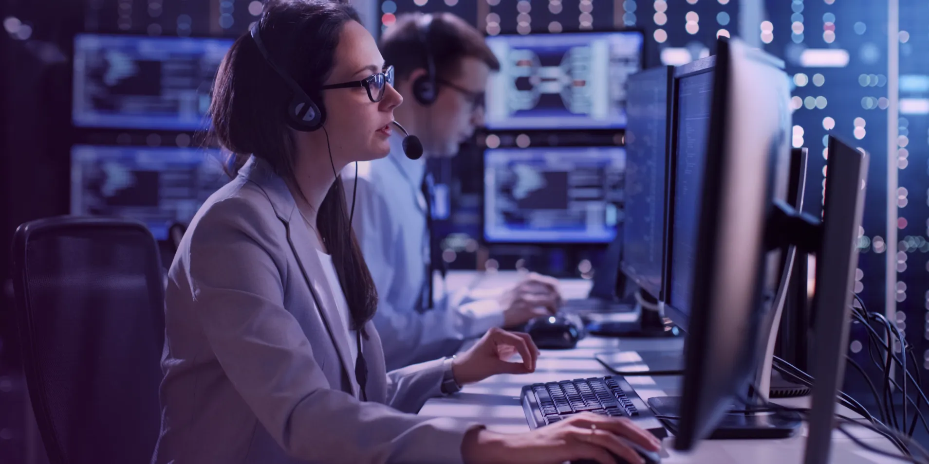 Professionals at computers with headsets in a control room, illustrating cybersecurity training environment