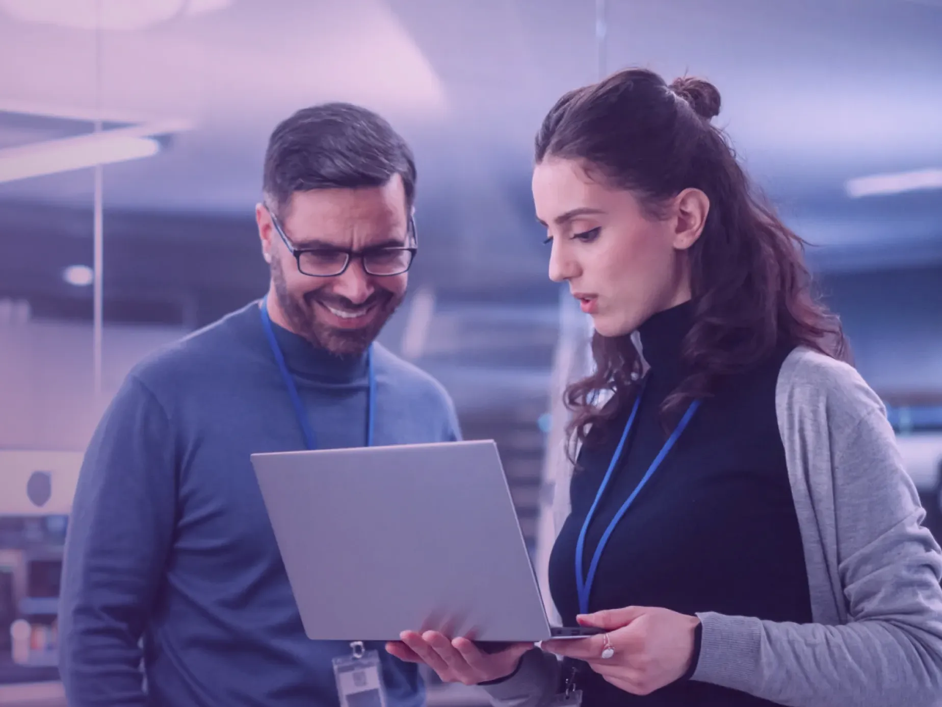 Two professionals discussing cybersecurity training on a laptop in an office setting