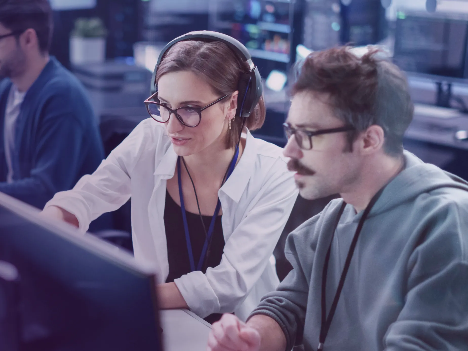 Two professionals at computers collaborating during cybersecurity training in a modern office environment