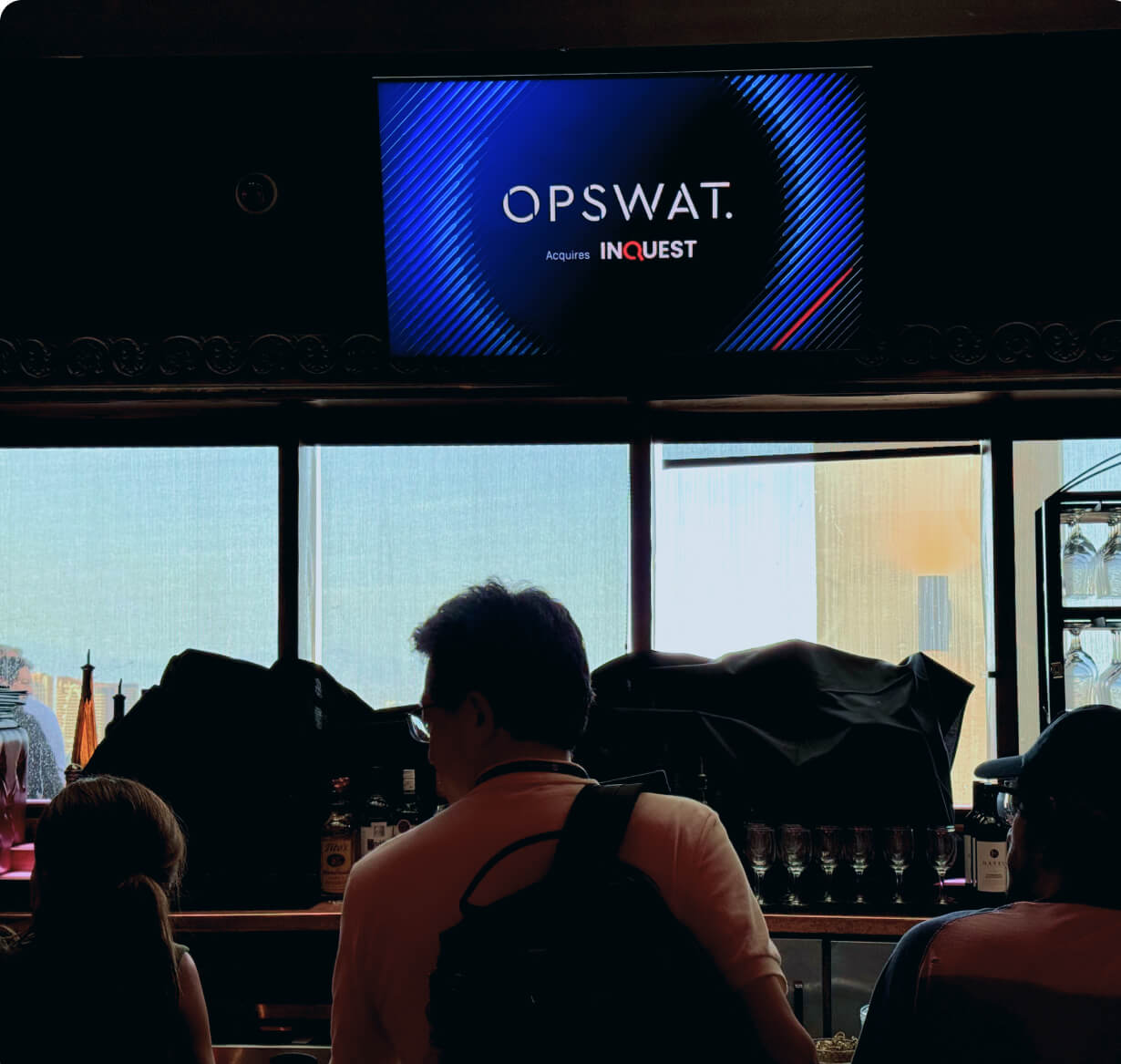 OPSWAT and INQUEST signage displayed at an event venue with attendees in the foreground