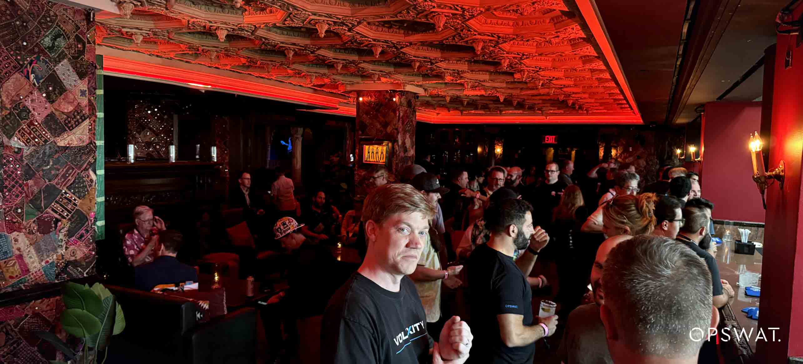Crowded OPSWAT event at a dimly lit venue with a lively atmosphere