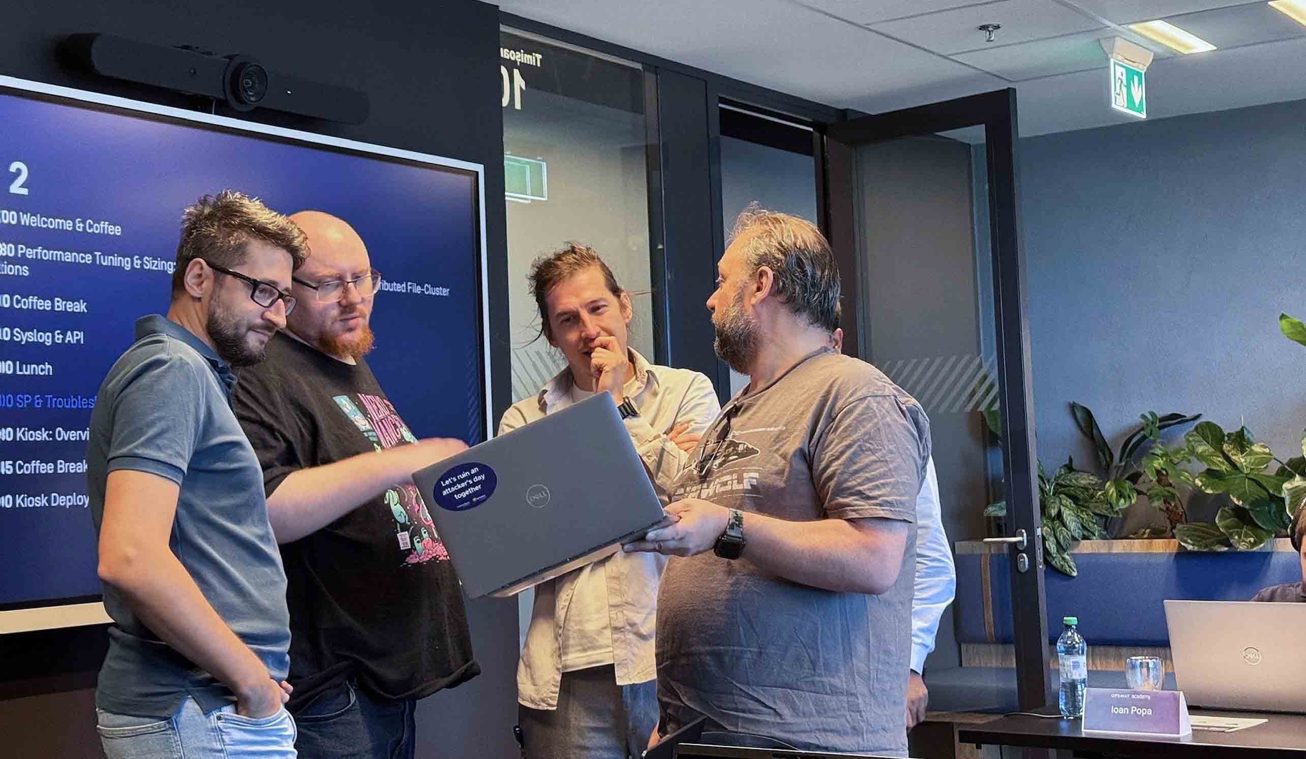 Four men collaborate at OPSWAT Academy international cybersecurity bootcamp in Timisoara, discussing at a laptop