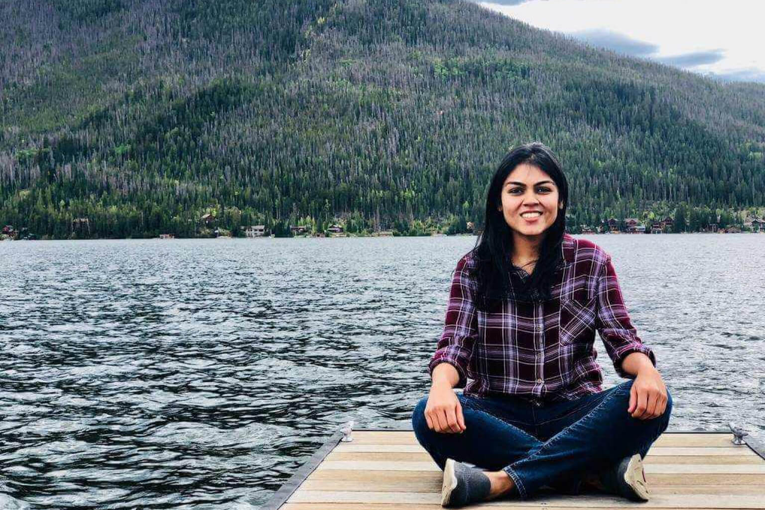 femme assise sur un quai devant un lac et une montagne