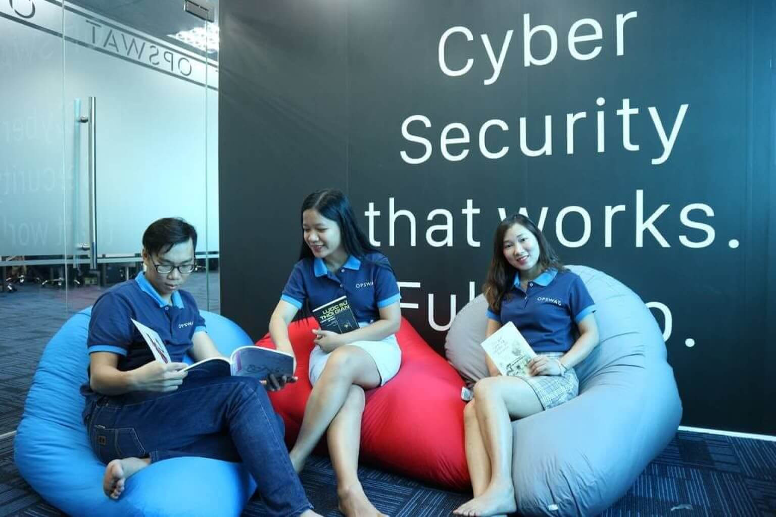 opswat des employés assis sur des poufs devant un panneau indiquant "la cybersécurité, ça marche".