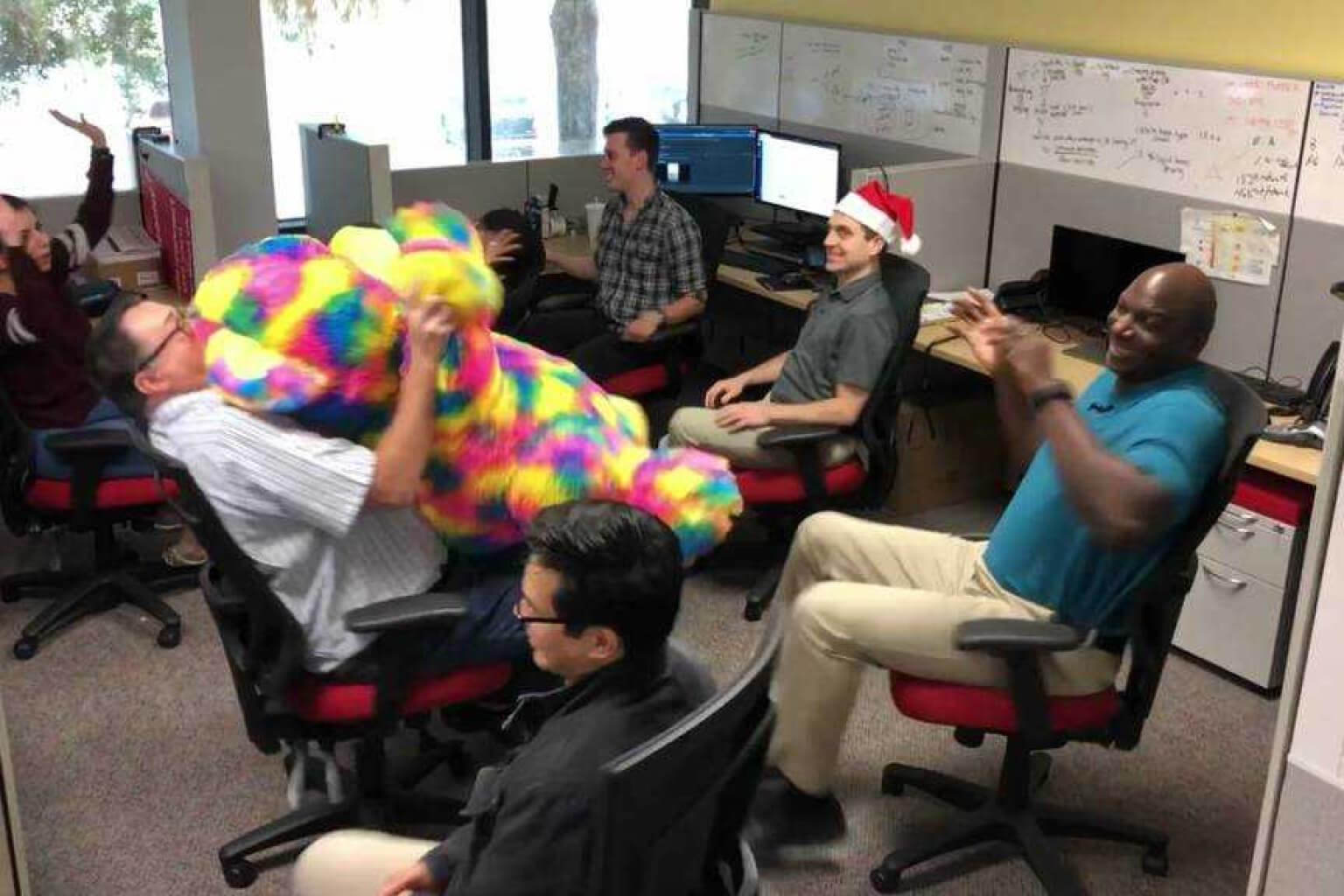 opswat des employés assis dans un bureau avec un grand animal en peluche multicolore