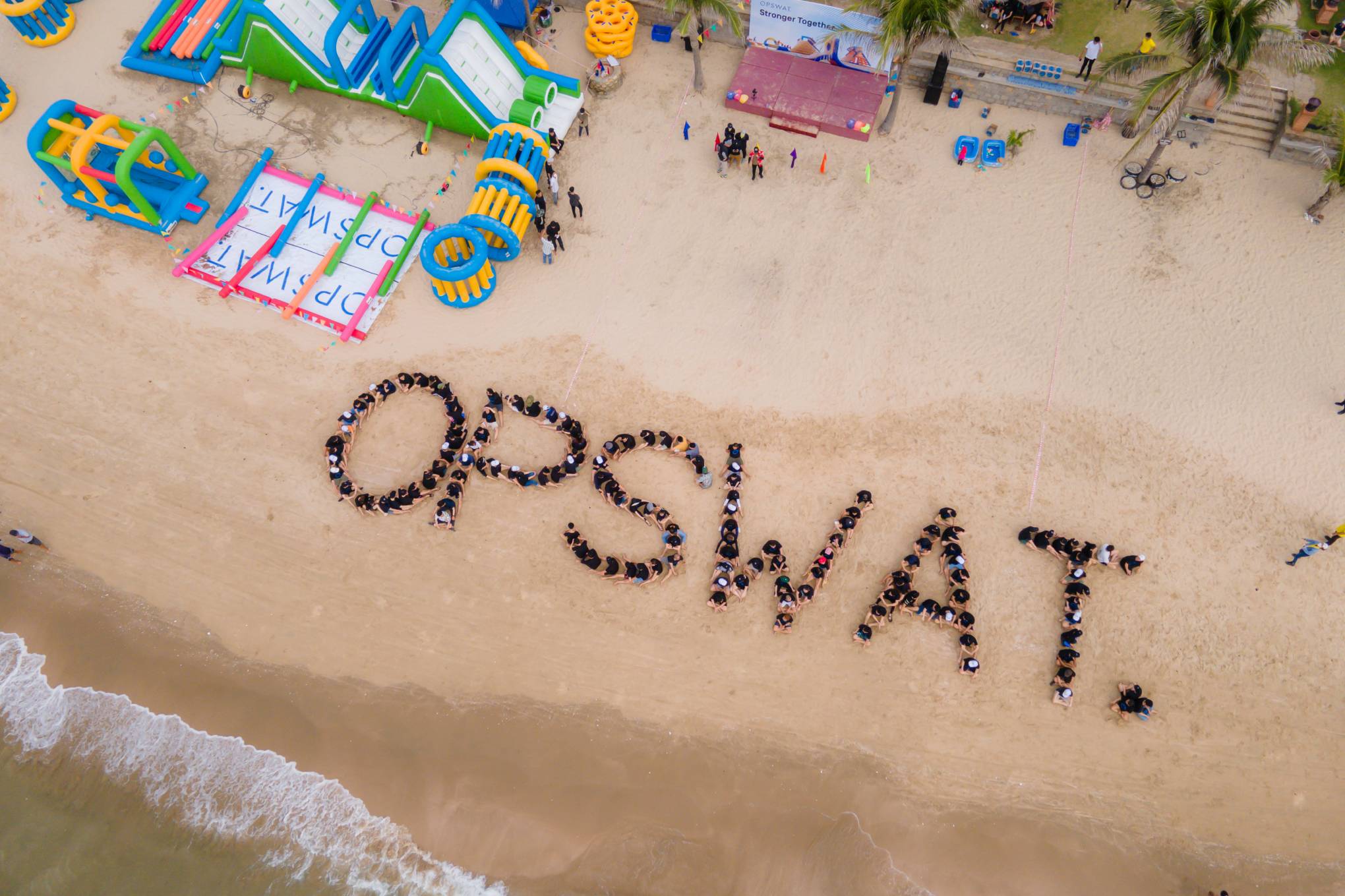 people standing together to spell out OPSWAT on a beach