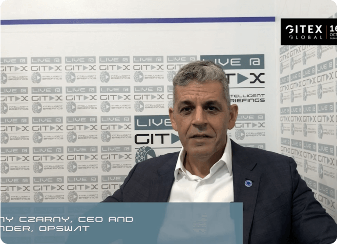 man in a suit sitting in front of a GITEX backdrop with text overlay "Benny Czarny, CEO and Founder, OPSWAT"