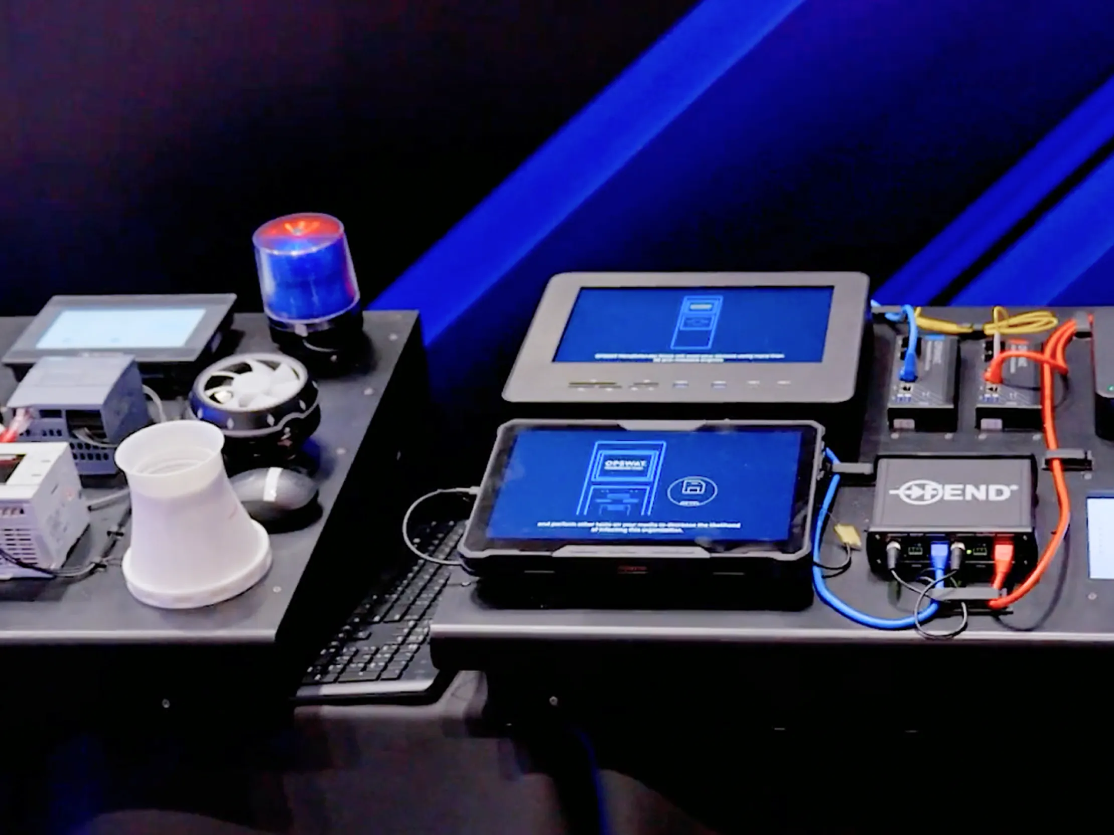 Display with cybersecurity hardware, monitors, and network devices on a table