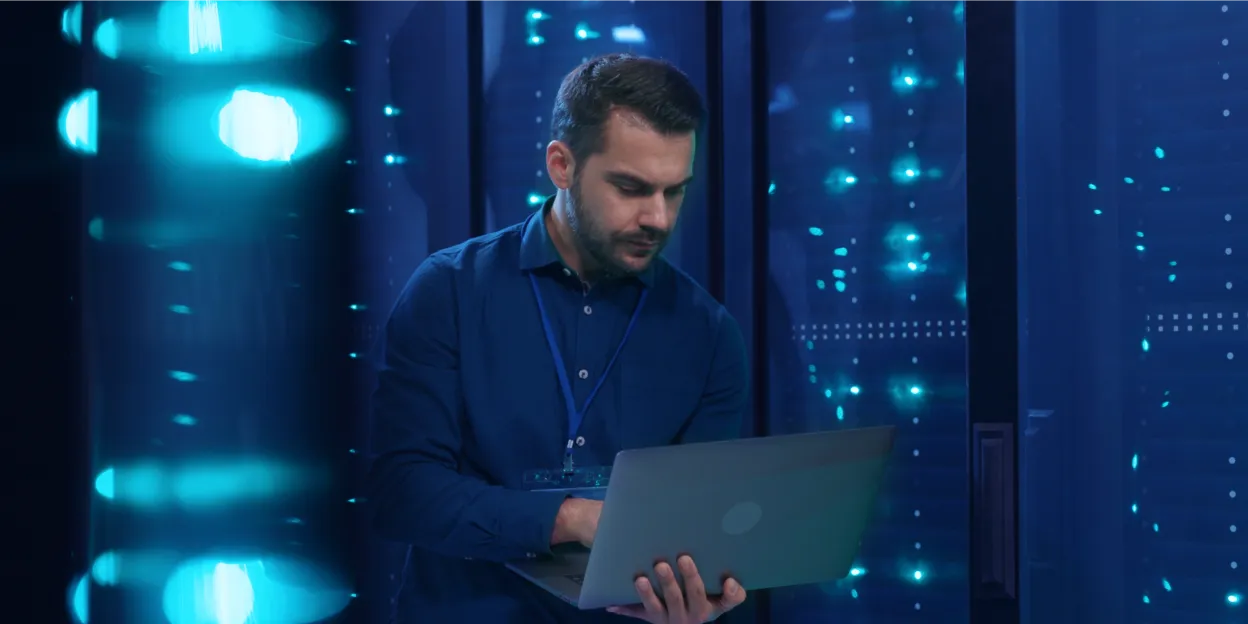 IT professional using laptop in server room, illustrating device posture check in secure environments