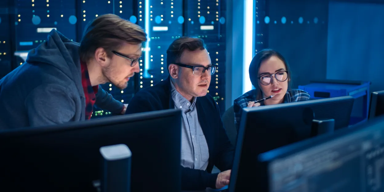 IT professionals review monitors in a server room, discussing device posture check for security